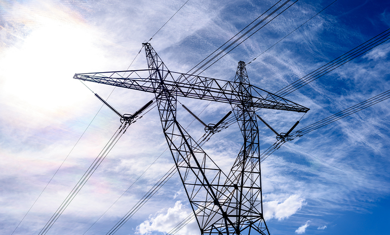 High voltage power transmission tower on blue sky background