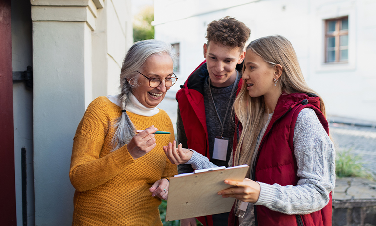 young volunteers talk to a senior woman with a clipboard