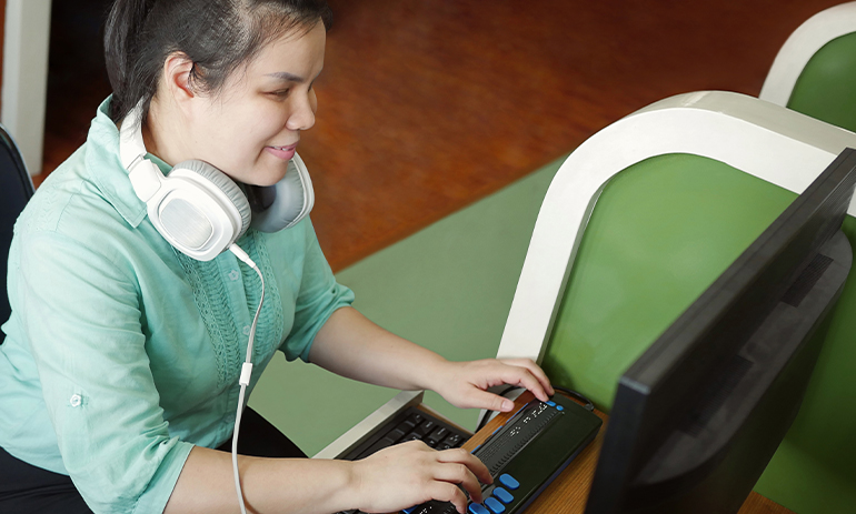 woman with vision impairment using a computer with a braille display