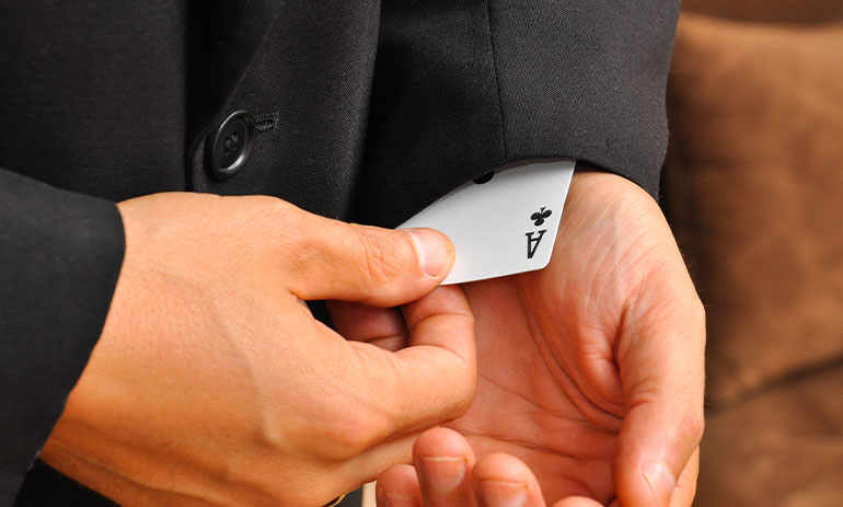 Image of person wearing suit with an ace playing card up their sleeve