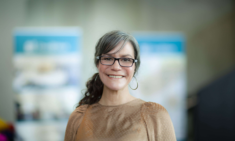 Kara Keys smiling with blurred background behind